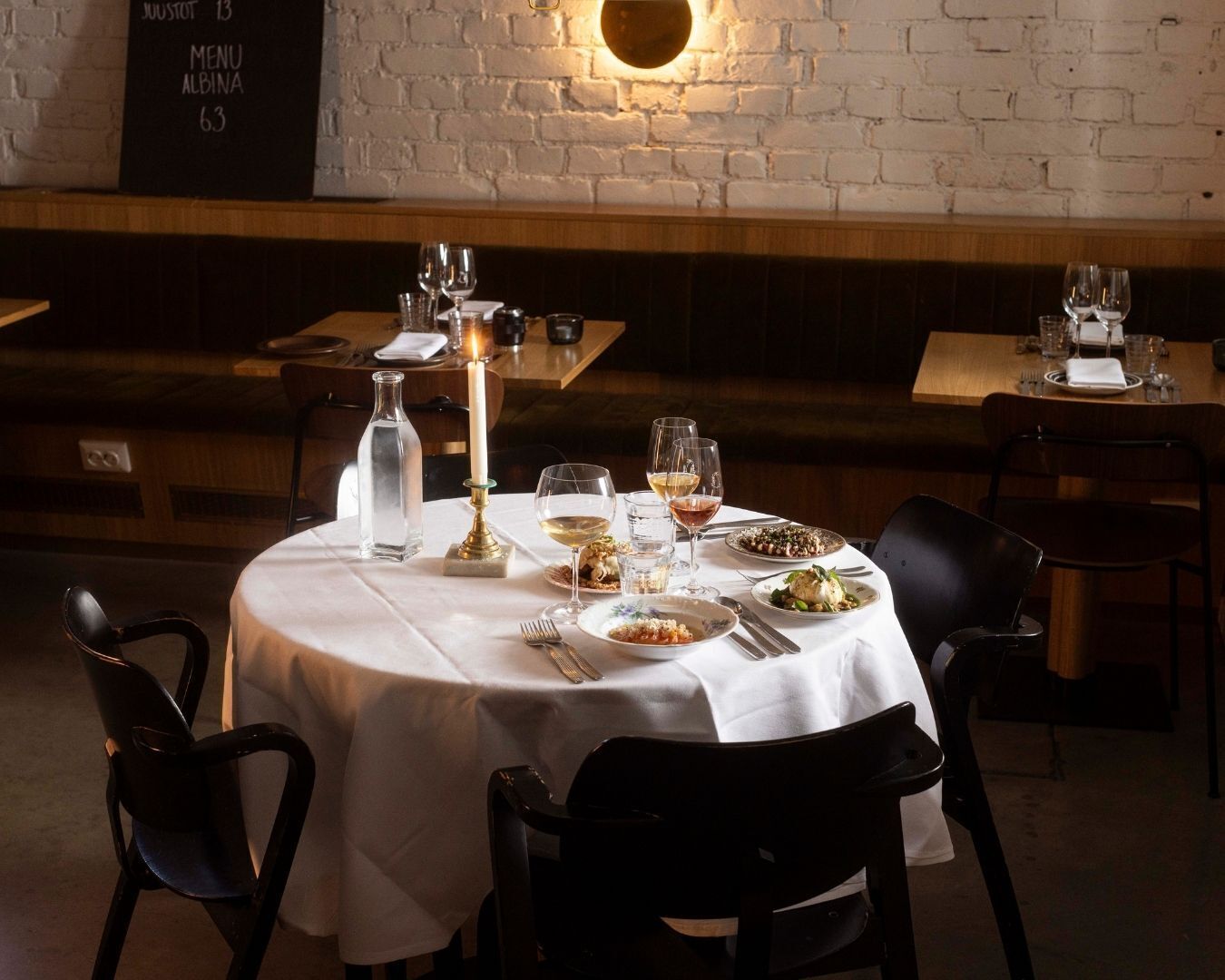 Une table de restaurant mise avec des assiettes, des verres et une bougie.