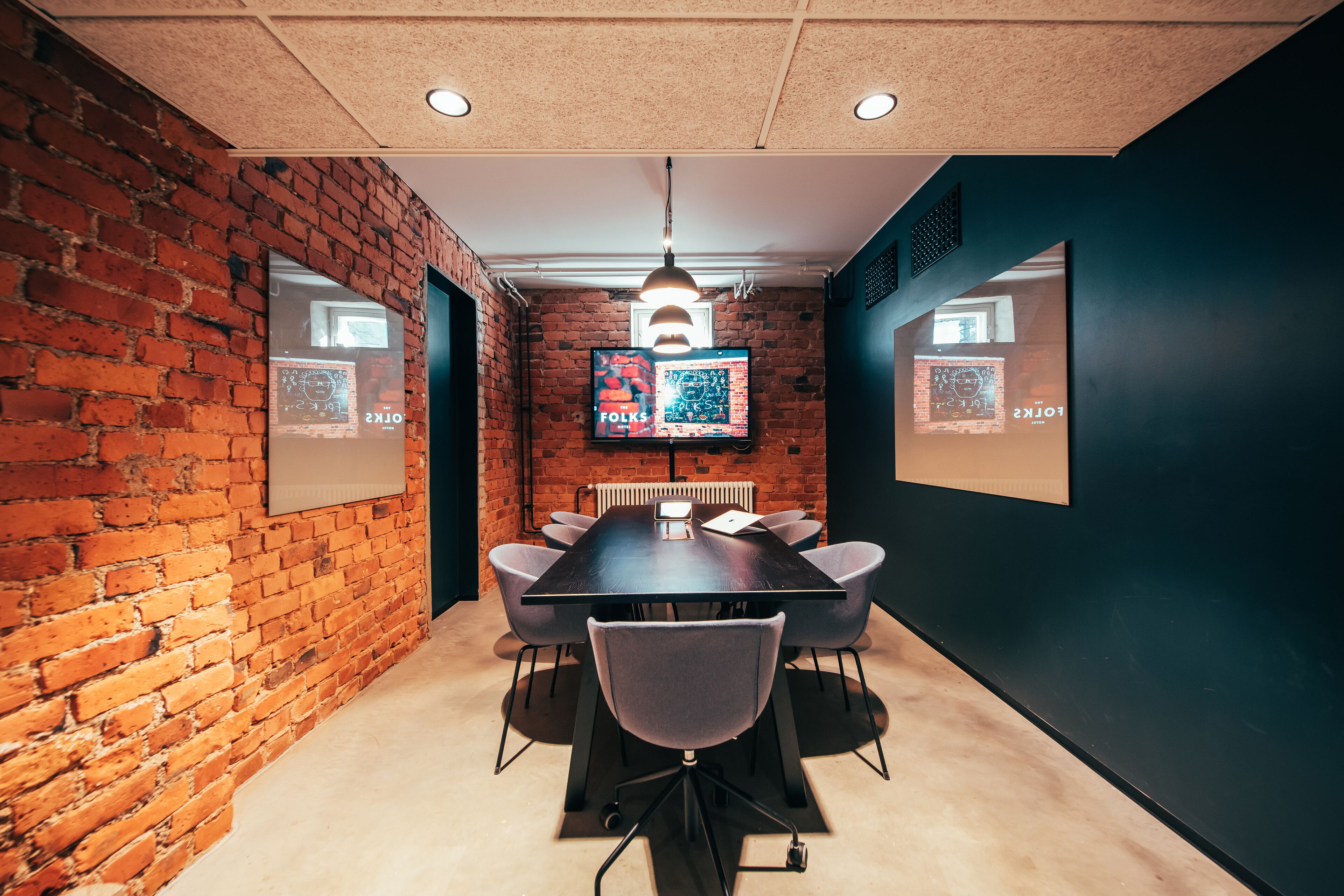 Un salón de conferencias con pared de ladrillo, una mesa grande y seis sillas.