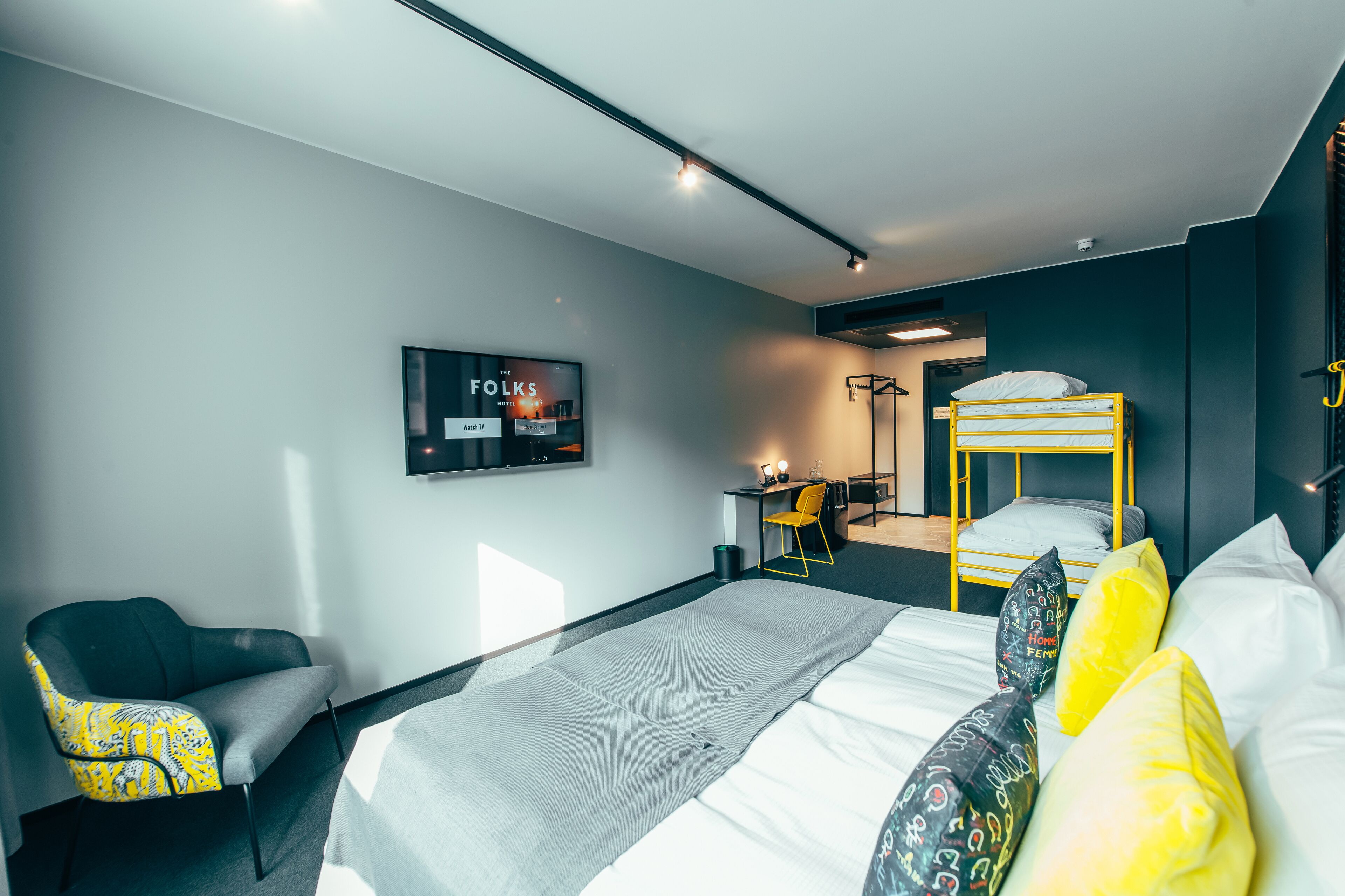 Una habitación de hotel moderna con una litera, un escritorio y una silla.