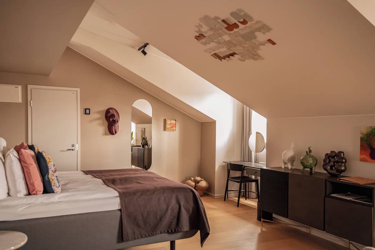 Un dormitorio con cama, escritorio, espejo y lámpara en el techo.