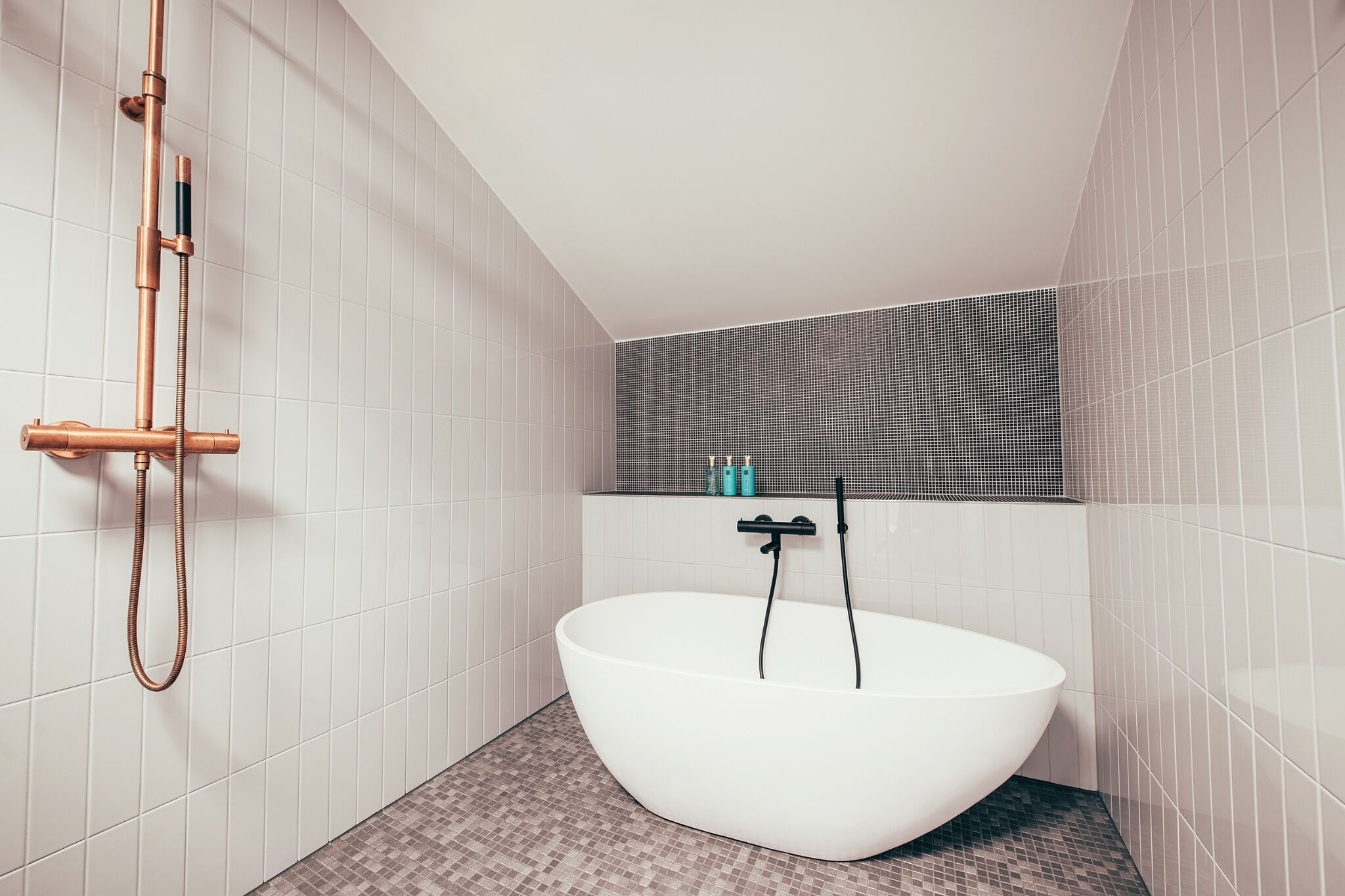 A modern bathroom with a freestanding bathtub, a showerhead, and a tiled floor.
