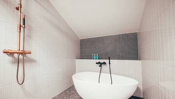 A modern bathroom with a freestanding bathtub, a showerhead, and a tiled floor.
