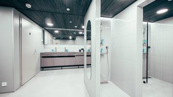 A modern bathroom with a shower, a vanity with a marble countertop, and a large mirror.