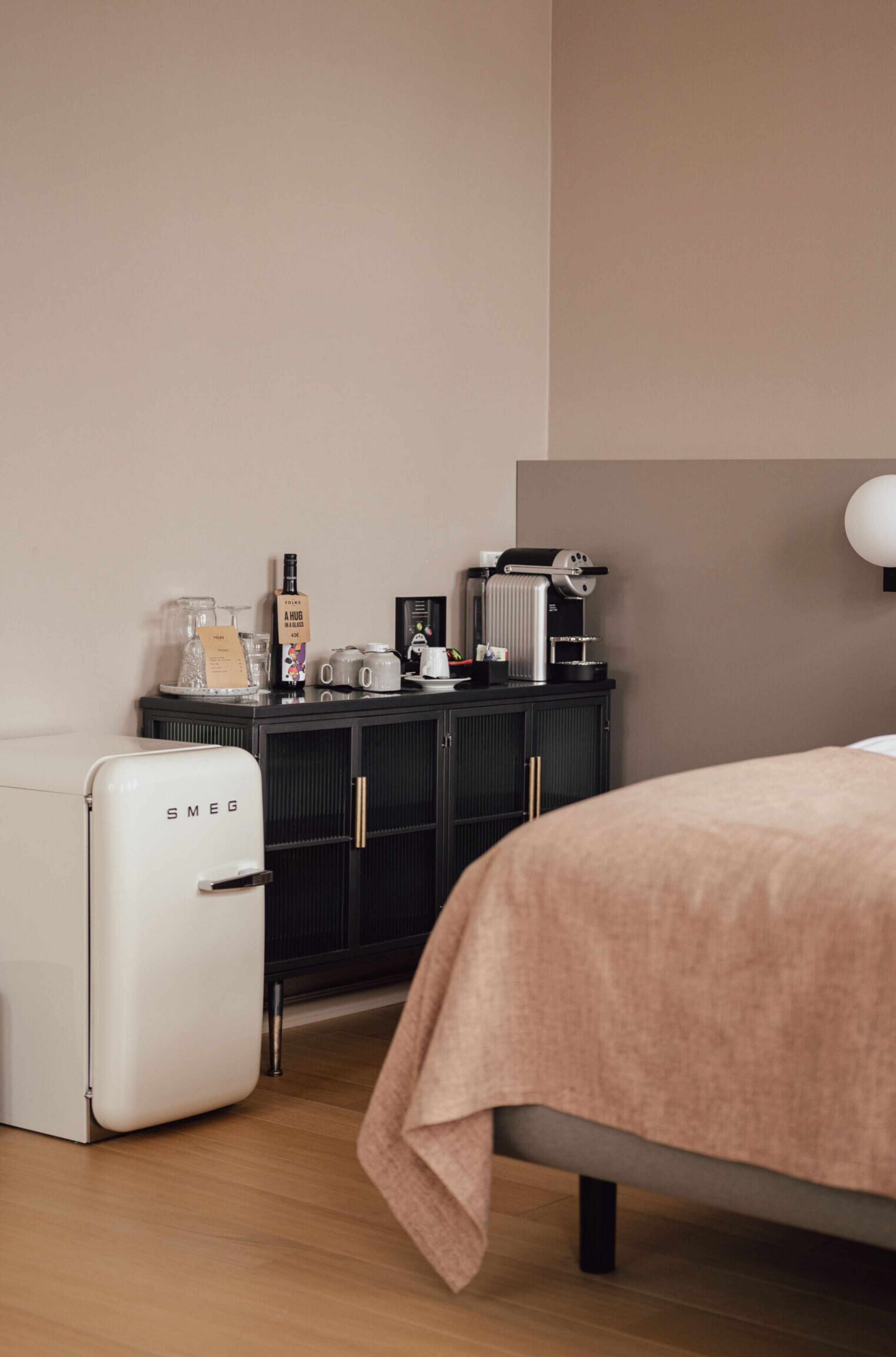 Un dormitorio con una cama, una pequeña kitchenette con cafetera, refrigerador y armario.