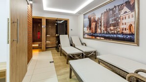 Ein Zimmer mit Holztür, einem Stadtbild in einem Rahmen, zwei Korbsessel mit Kissen und einer Bank.