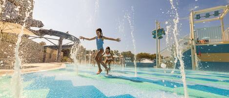 A water play area with multiple water jets and a slide.
