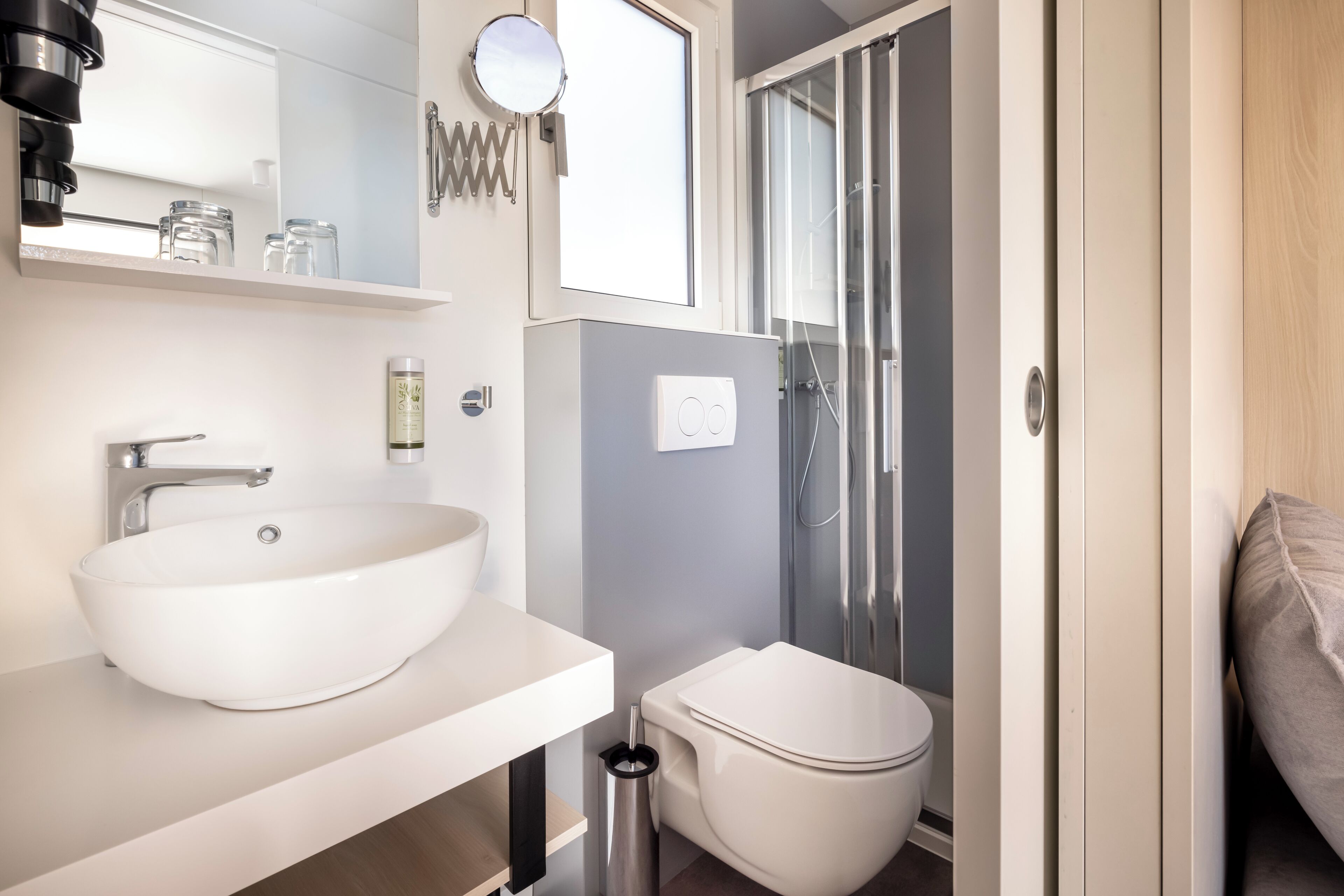 Un baño moderno con un lavamanos blanco, inodoro y cabina de ducha con mampara de vidrio.
