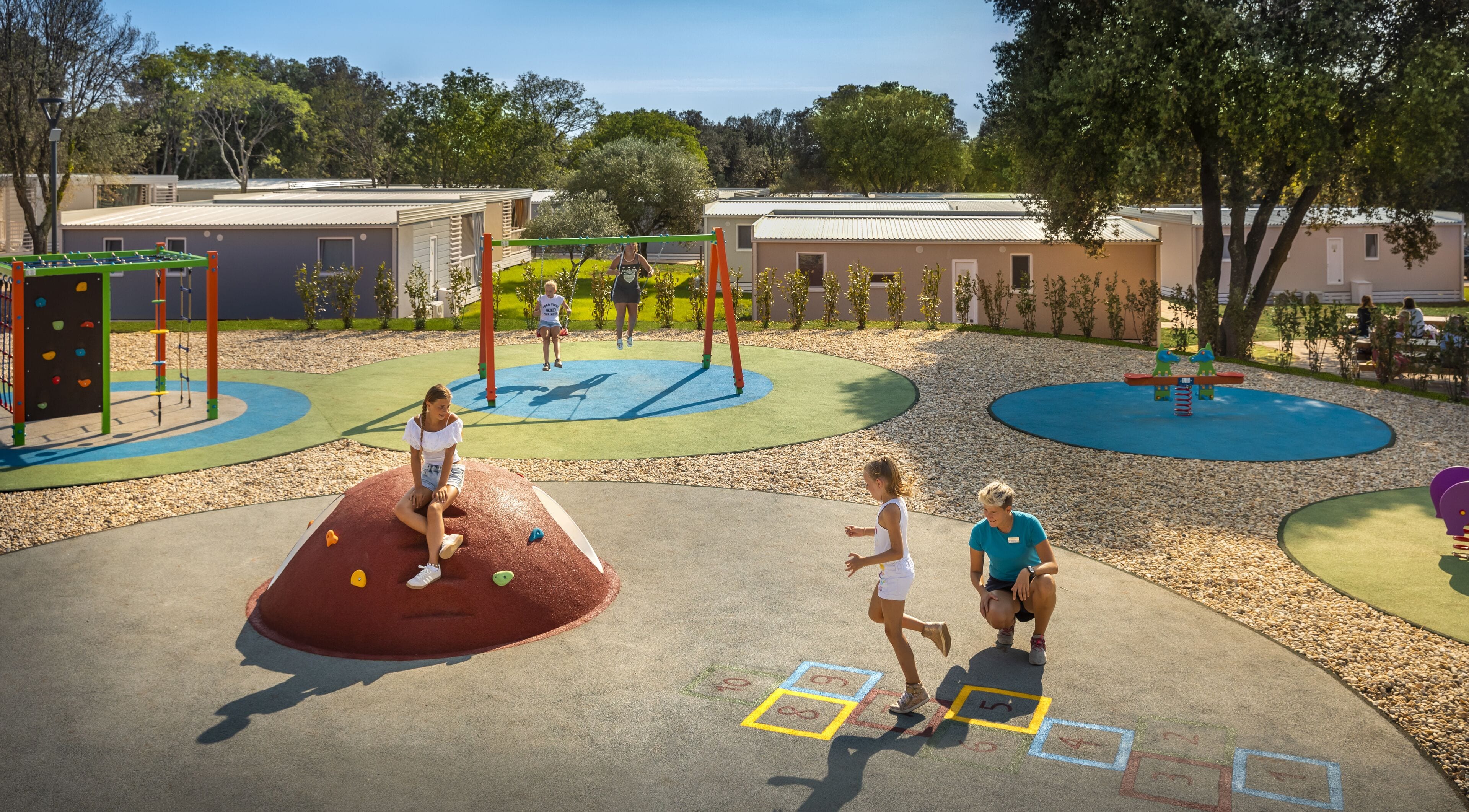 A playground with climbing structures, a hopscotch game, and a sandbox area.