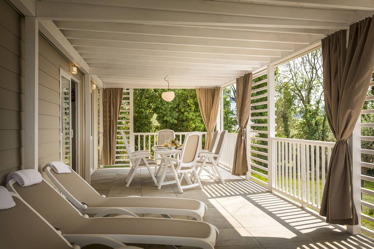 A covered outdoor area with lounge chairs, a table, and chairs.
