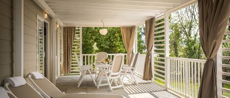 A covered outdoor area with lounge chairs, a table, and chairs.