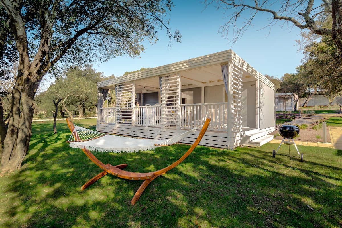 A wooden deck with a hammock and a barbecue grill.
