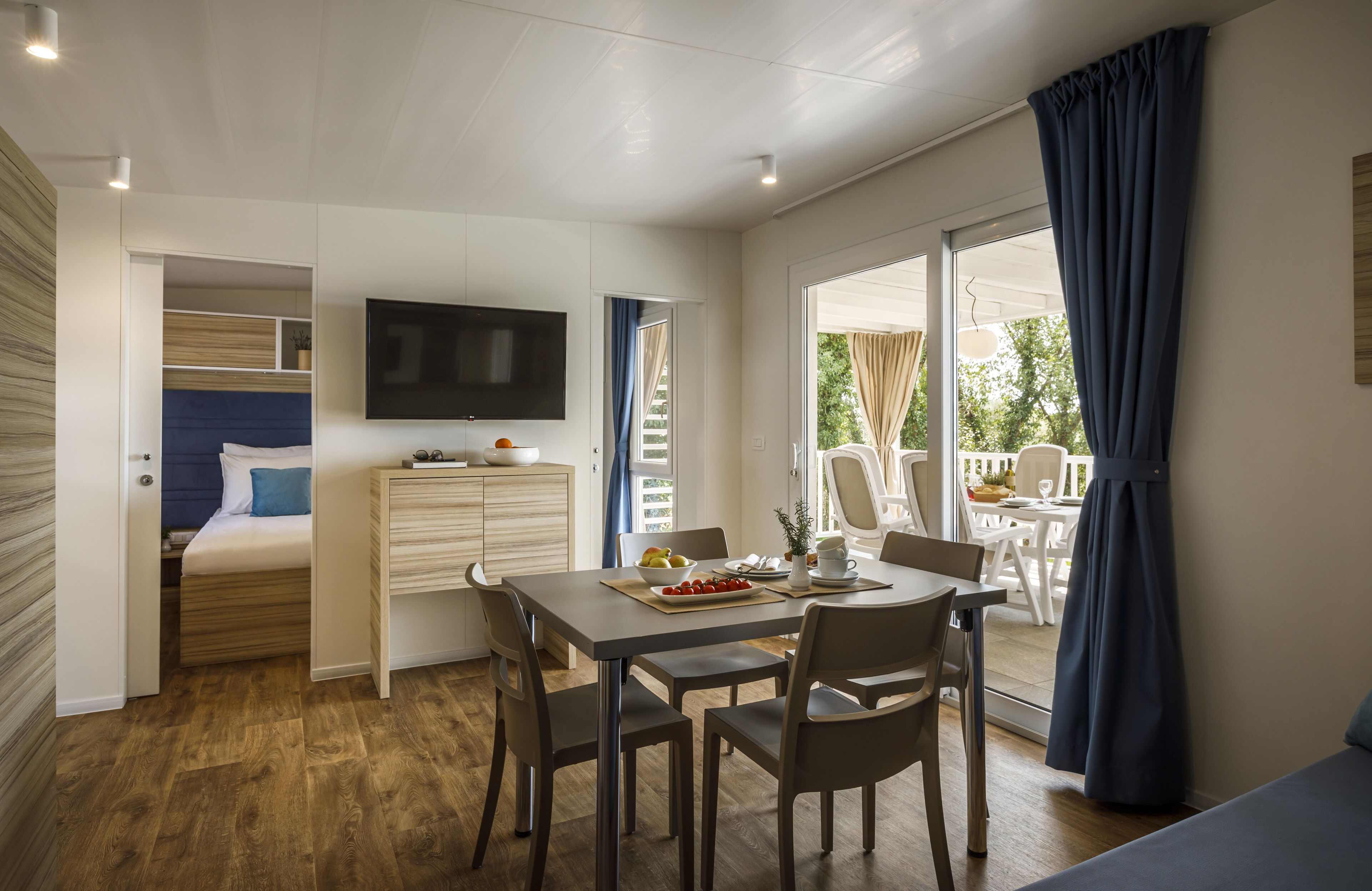 A modern room with a bed, a dining table, and a TV.