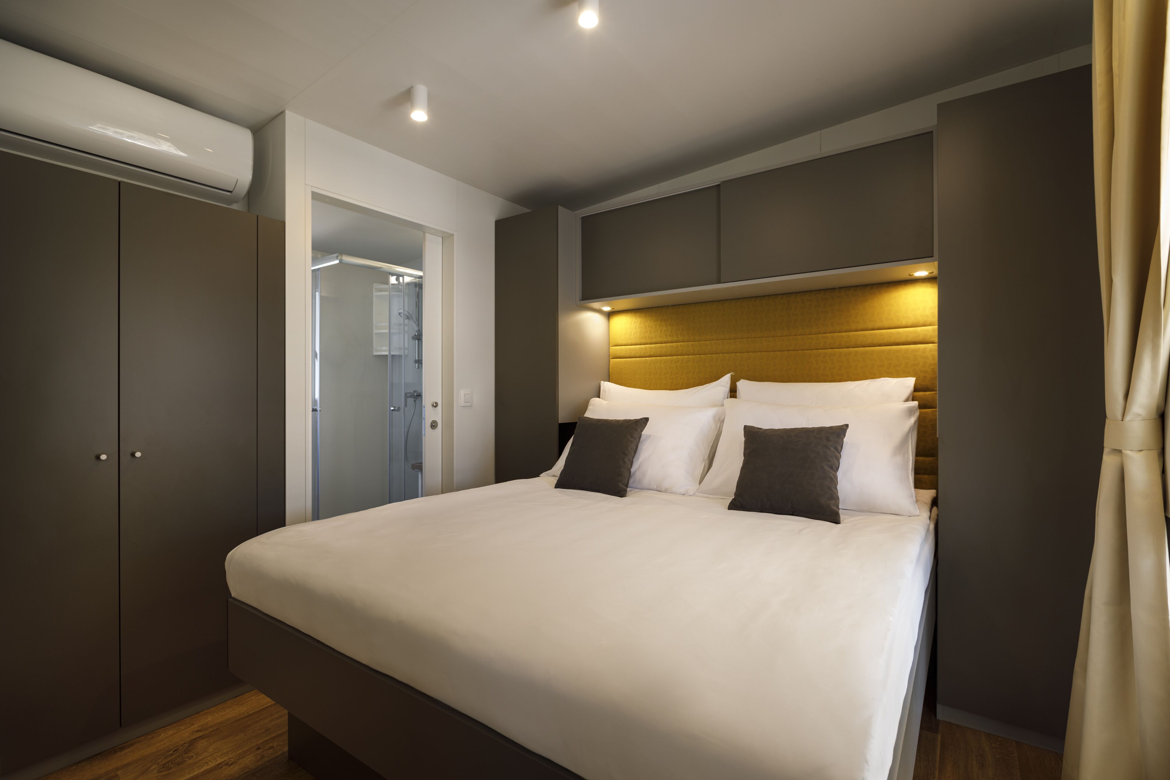 A modern bedroom with a large bed, built-in wardrobe, and a walk-in closet.
