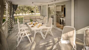 Un portico coperto con tavolo e sedie, un divano e una cucina visibile attraverso le porte in vetro.