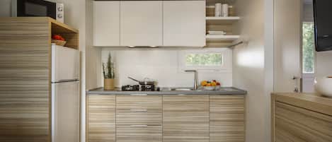 A modern kitchen with wooden cabinets, a built-in microwave, and a window above the sink.