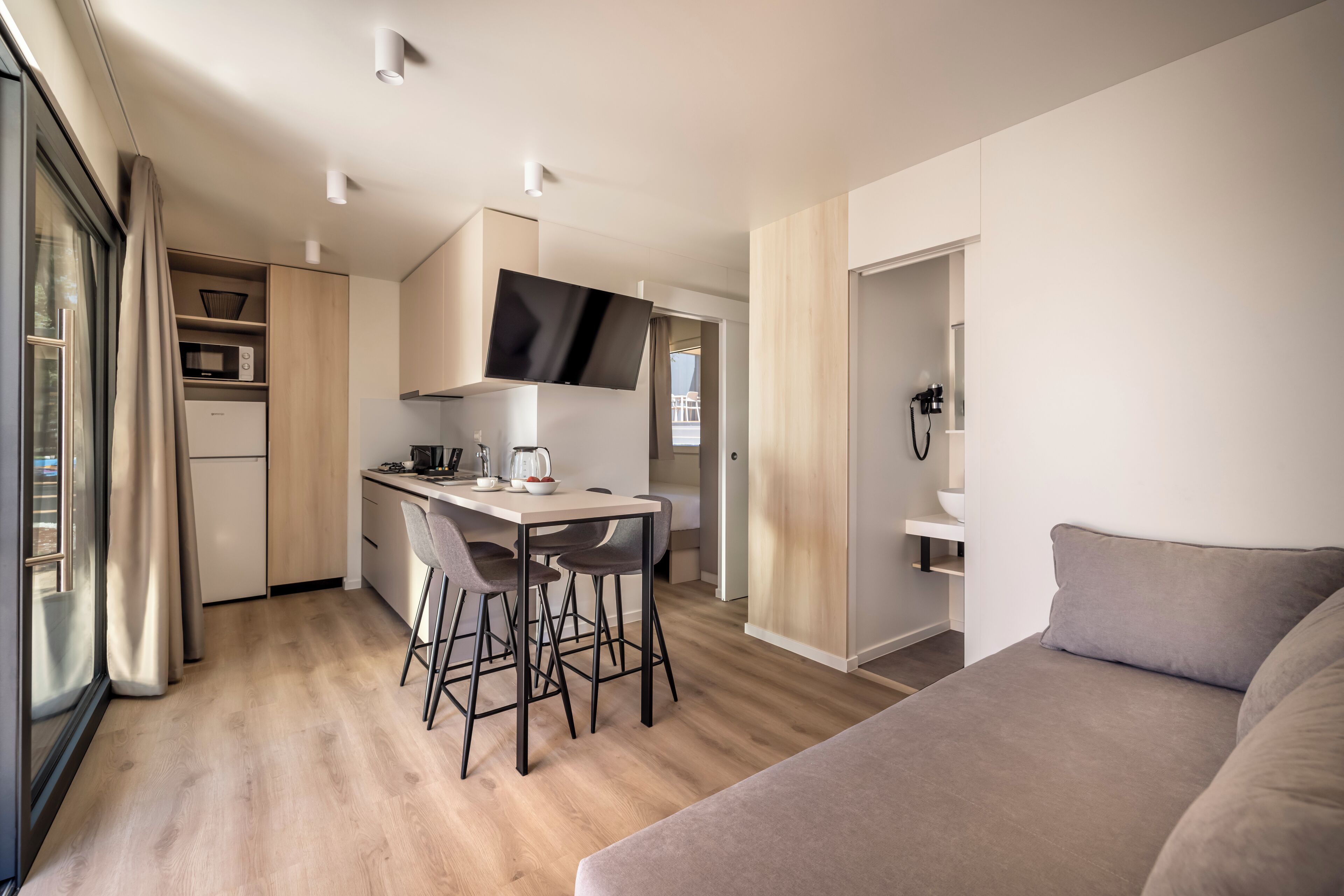 Ein modernes, kompaktes Wohnzimmer mit Küchenzeile, Essbereich und einem großen Bett.
