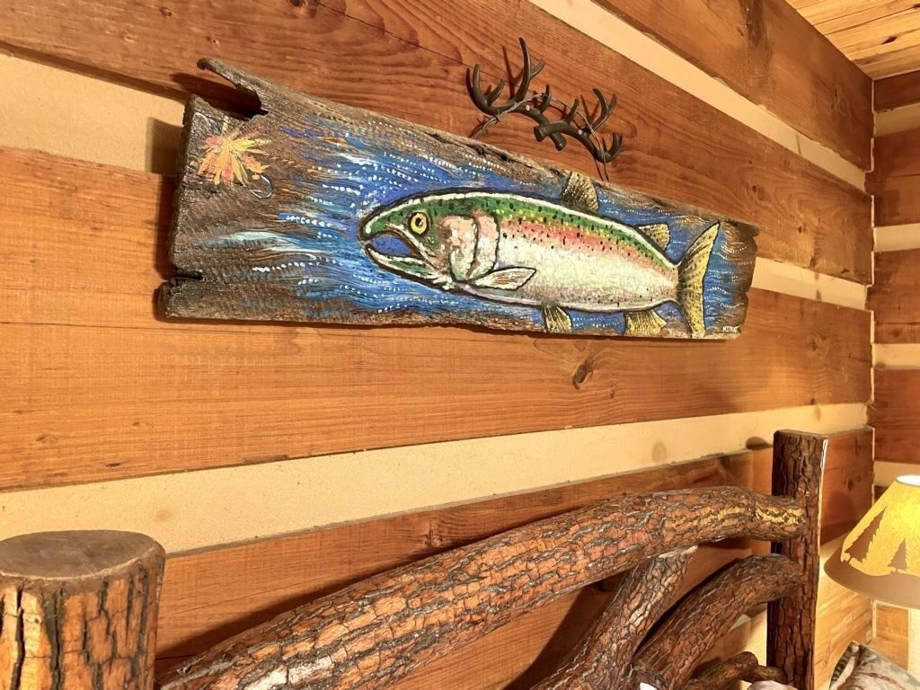 A wooden wall with a painted fish and antlers.