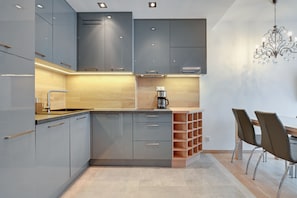A modern kitchen with grey cabinets, a wooden countertop, and a chandelier. - Happy Stay OldNova Deluxe Apartment 366 (Gdansk)