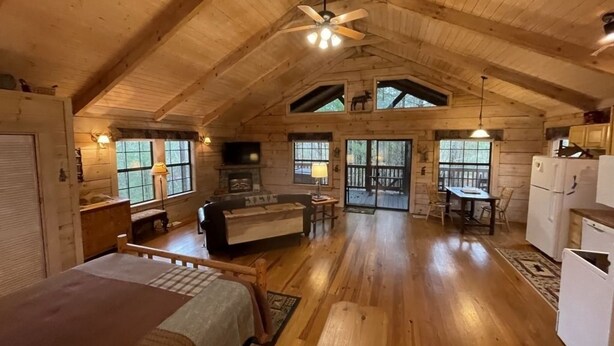 A spacious log cabin with a high ceiling, a cozy living area with a sofa and fireplace, a dining area, and a kitchen. - Private and Perfect! - hot tub, king bed, fireplace - dog and motorcycle friendly Studio Cabin by RedAwning (Tellico Plains)