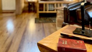A cozy room with wooden walls and a wooden floor. There is a table with a lamp and a red book on it. - Private and Perfect! - hot tub, king bed, fireplace - dog and motorcycle friendly Studio Cabin by RedAwning (Tellico Plains)