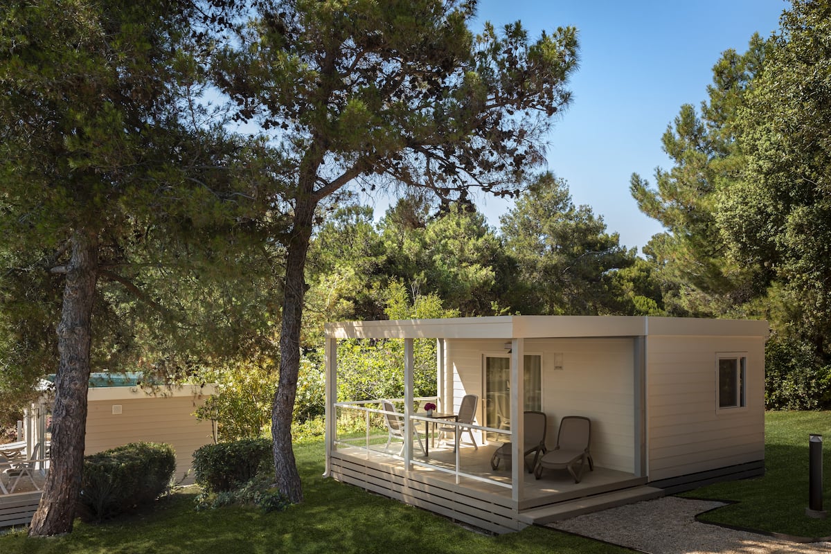 A modern cabin with a covered porch, a dining area, and a small pool.