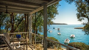 A covered outdoor area with a view of boats on a lake, surrounded by trees.