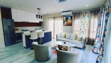 Una sala moderna con sofá, una mesa de centro y una zona de cocina con armarios y un refrigerador.
