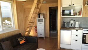 Ein gemütliches Blockhaus-Interieur mit einer Holztreppe, einer Küchenzeile, einer Couch und einem kleinen Tisch.