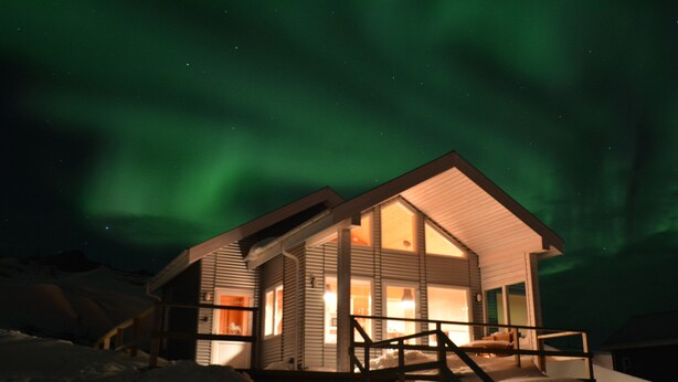 Ein zweistöckiges Lodgehaus mit überdachter Veranda und einer Treppe zum Eingang.