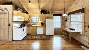 Une cuisine de style rustique, avec des murs en bois, un poêle, un réfrigérateur et des armoires en bois.