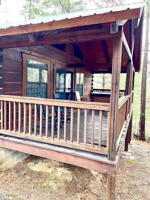 A wooden cabin with a covered porch, large windows, and a dining area. - Perfectly private! Hot tub, king sized bed, grill, washer/dryer, and motorcycle friendly! Studio Cabin by RedAwning (Tellico Plains)