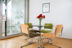 A modern dining area with a glass table, two green cushioned chairs, and a vase with red flowers. - Marimari Apartment, 4th floor with elevator (Split)
