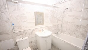 Une salle de bain comprenant des toilettes, un lavabo, un miroir et une baignoire.