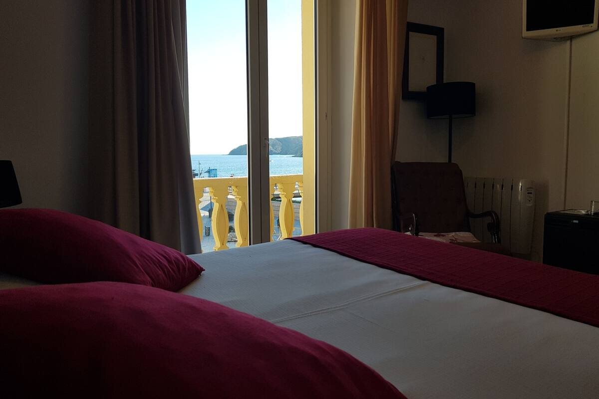 Une chambre d’hôtel avec un lit, une chaise, une télévision et vue sur la mer.