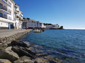 A coastal town with white buildings, a rocky shoreline, and boats in the water. - Hotel La Residencia (Cadaqués)