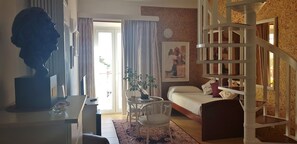 A living room with a sofa, a dining table, a staircase, and a large window with curtains. - Hotel La Residencia (Cadaqués)