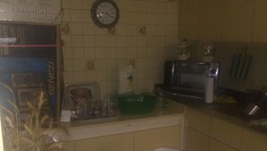 Een keuken met een eettafel, stoelen, een klok en een magnetron.