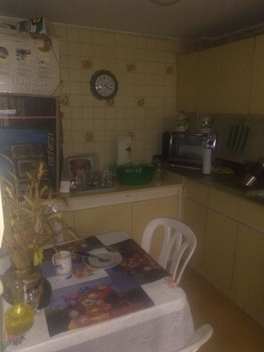 A kitchen with a dining table, chairs, a clock, and a microwave.
