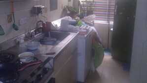 Een keuken met een fornuis, spoelbak en diverse keukenbenodigdheden.
