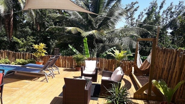 A wooden deck with lounge chairs, a small table, and a hammock. - The Island Experiences-Samo (Choiseul)