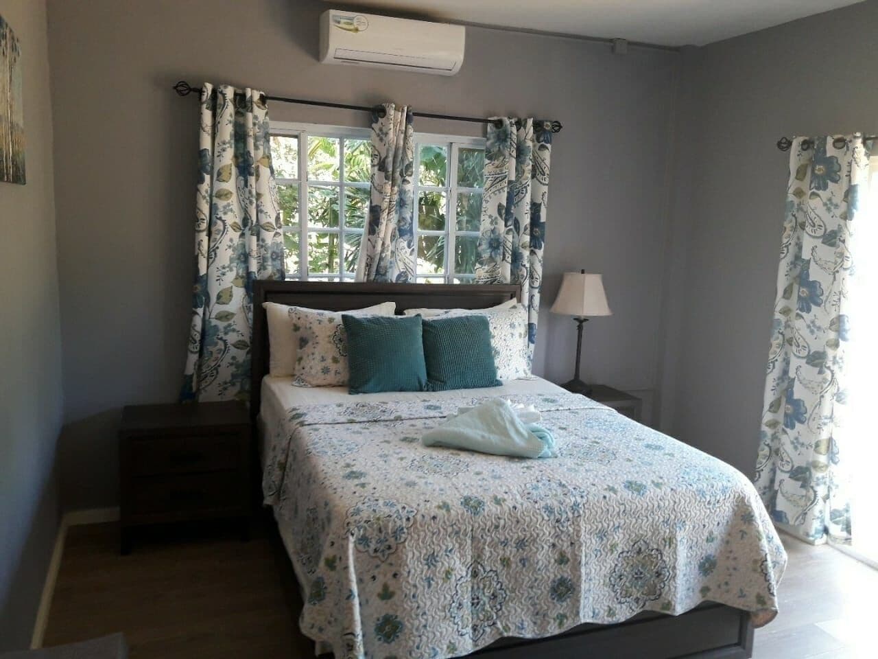 A bedroom with a bed, a nightstand, a lamp, and a window with curtains.