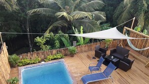 A wooden deck with a hot tub, lounge chairs, and a table. - The Island Experiences-Samo (Choiseul)