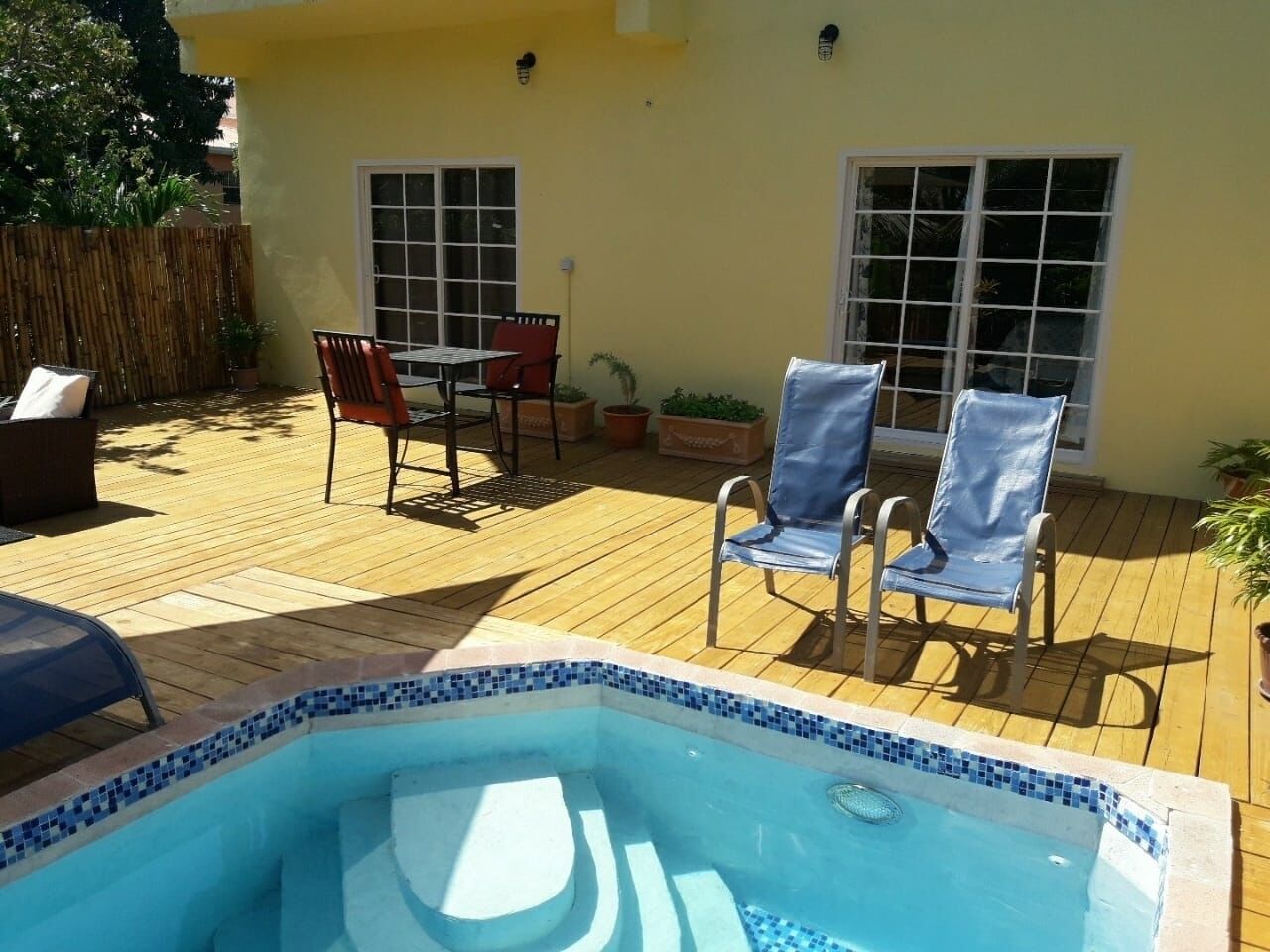 A backyard with a hot tub, wooden deck, and outdoor furniture.