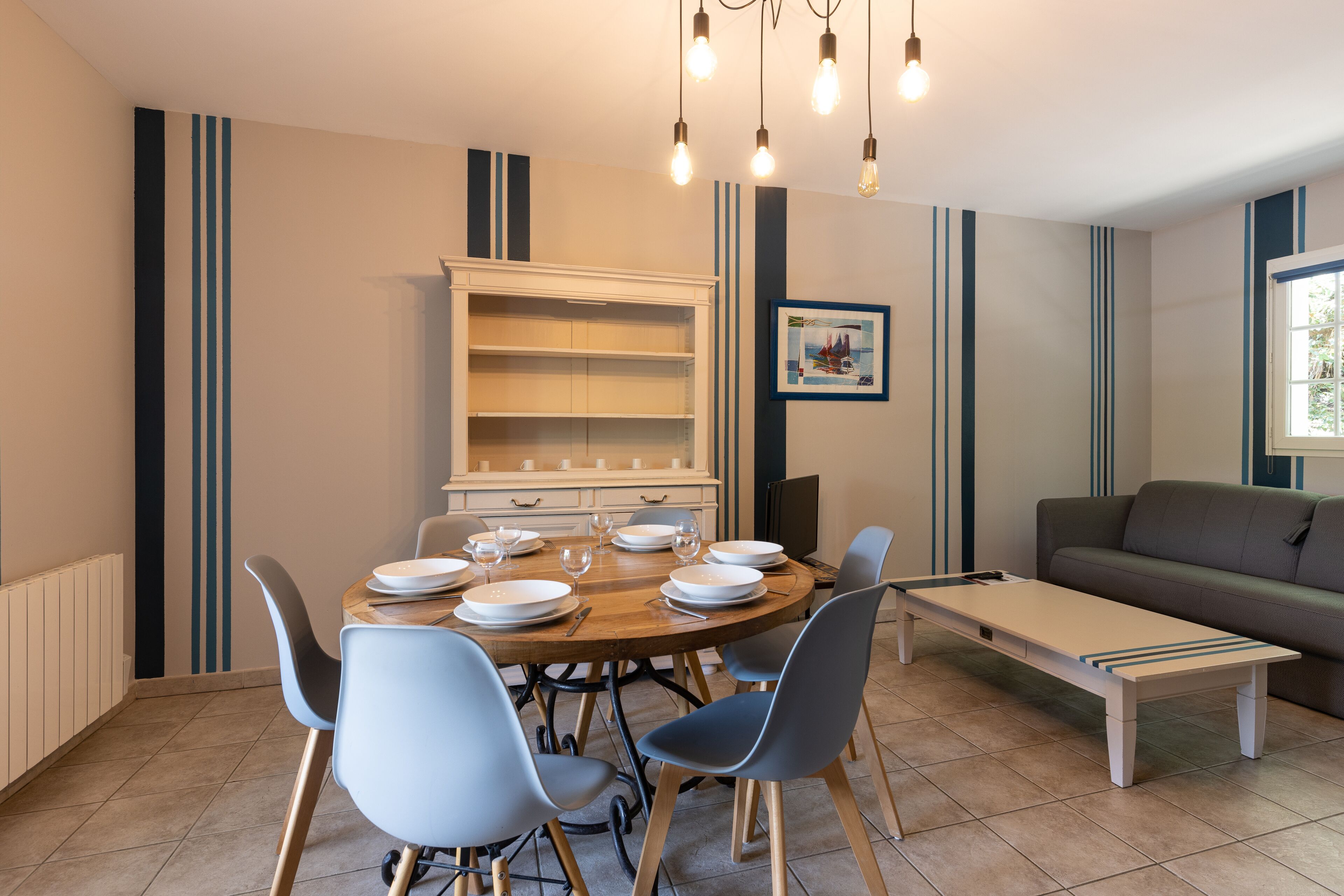 A dining area with a round table, chairs, and a cabinet.