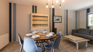 A dining area with a round table, chairs, and a cabinet.