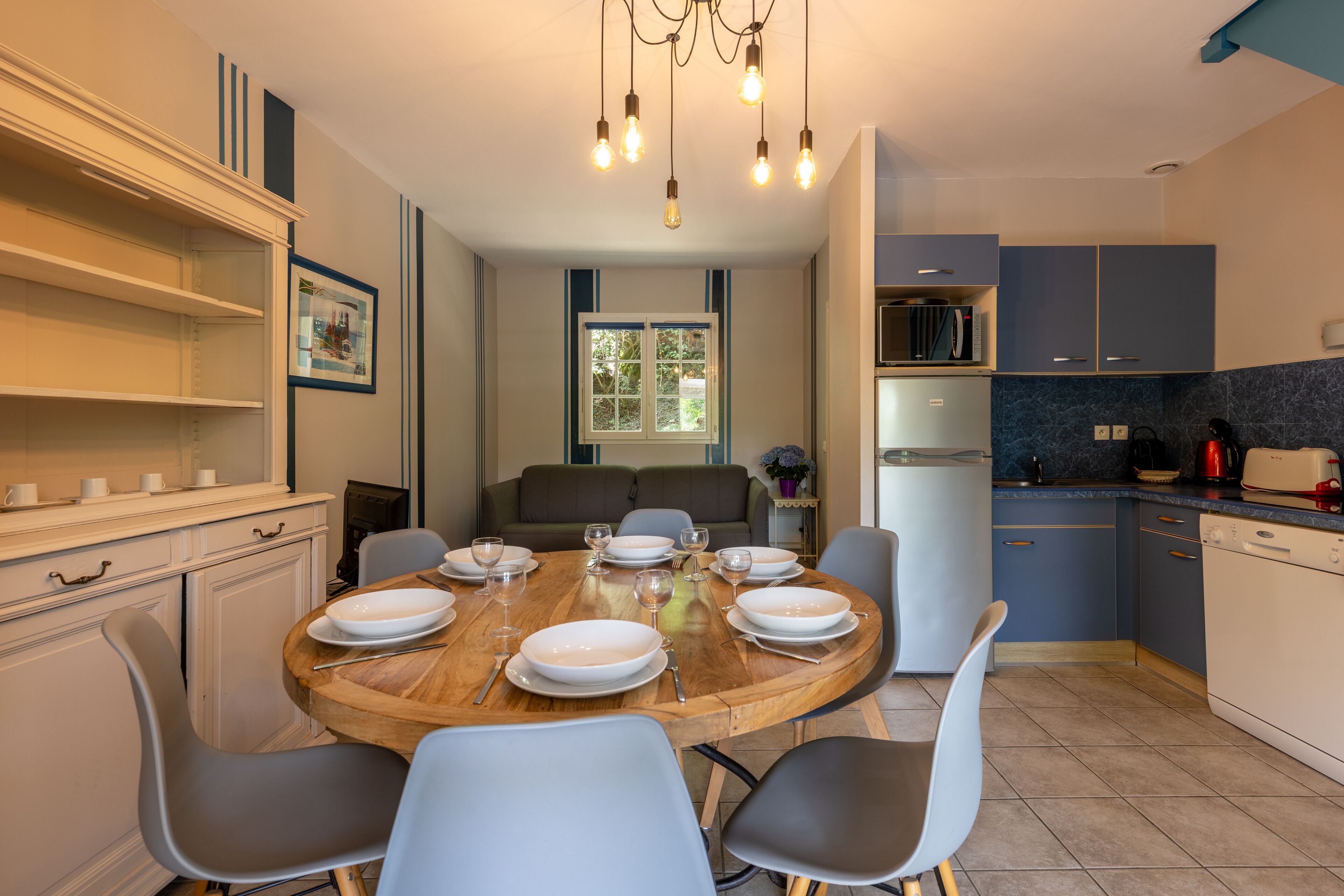 Una cocina moderna con una mesa de comedor para cuatro personas, un microondas y un lavavajillas.