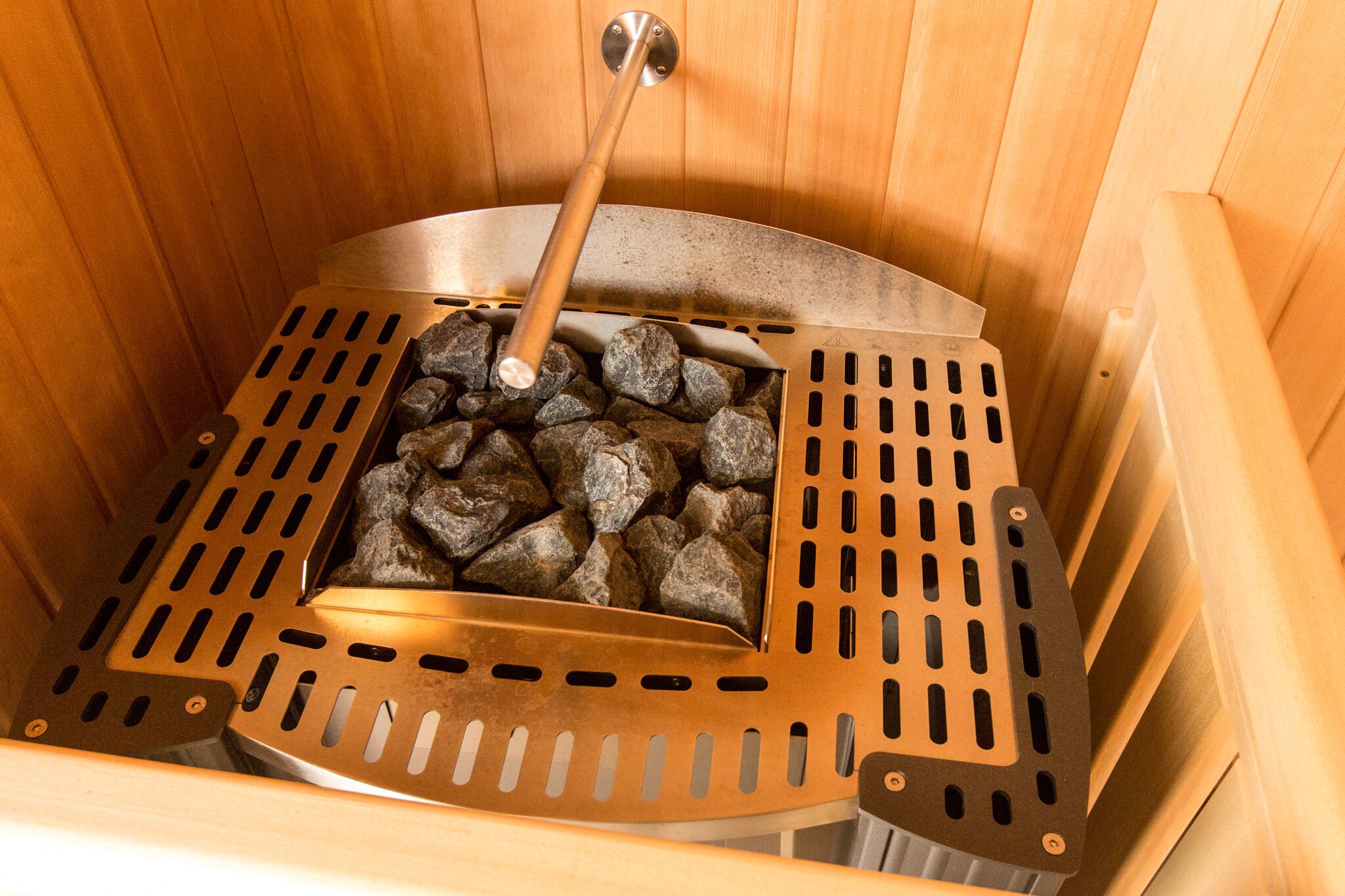 Uma sauna com uma grelha de metal cheia de pedras e um banco de madeira.