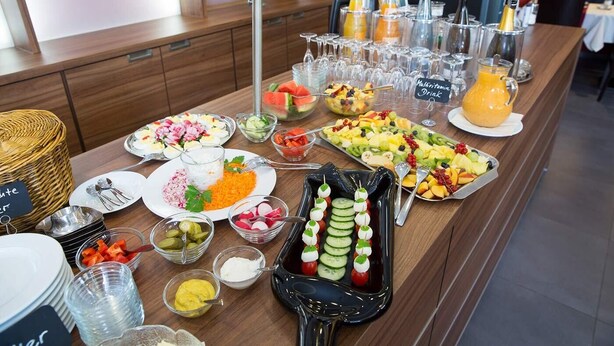 A buffet table with various food items, drinks, and condiments.