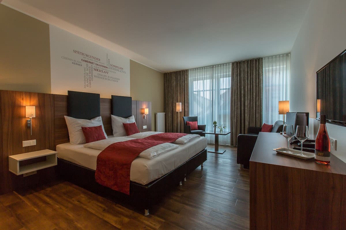 Een moderne hotelkamer met een groot bed, nachtkastjes, een bureau en een grote spiegel.