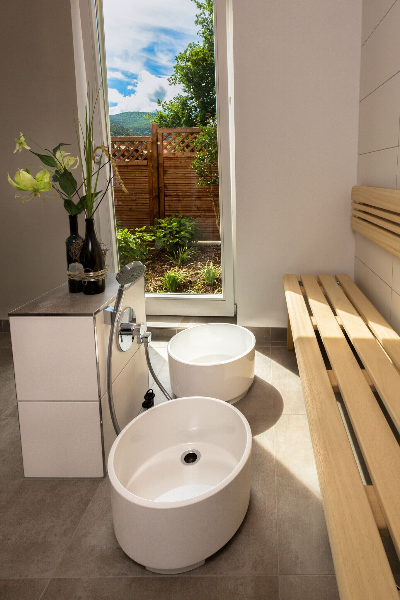 A modern bathroom with two sinks, a shower, and a bench.